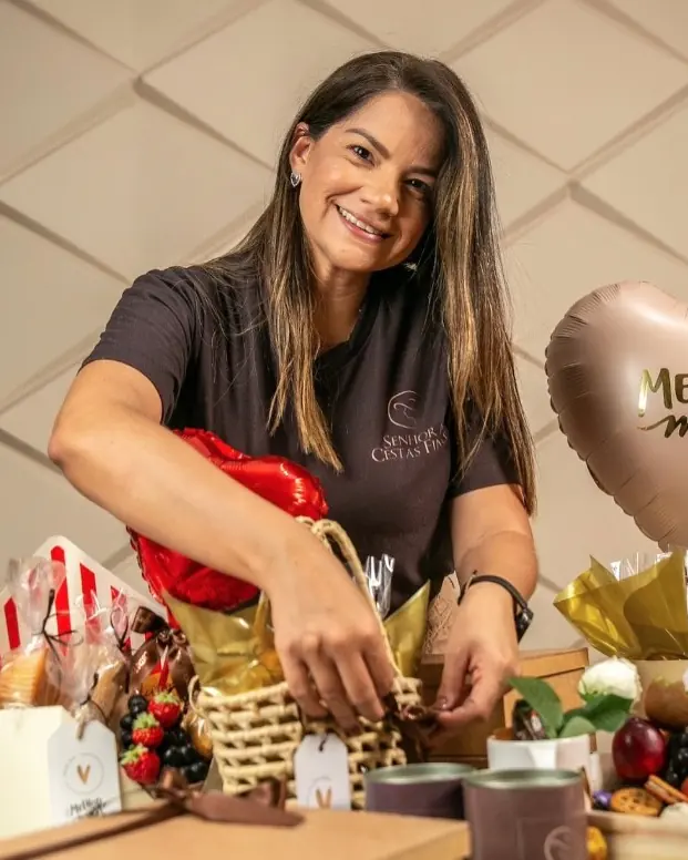 Jaqueline Formiga, de camiseta da Senhora Cestas Finas, montando uma cesta com balões em formato de coração
