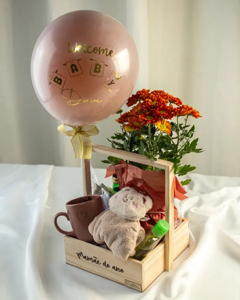 Cesta Welcome Baby em caixa de madeira com balão rosé, flores laranja, caneca e naninha de urso