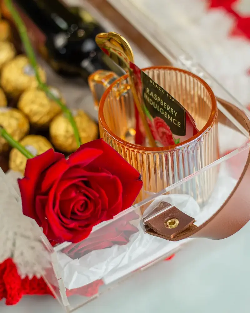Detalhe da Forever Us Love com rosa vermelha, chocolates e caneca de vidro dentro do baú de acrílico
